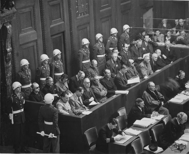 Fotografia histórica em preto e branco dos réus do regime nazista e dos guardas no julgamento em Nuremberg, cerca de 1945 a 1946.