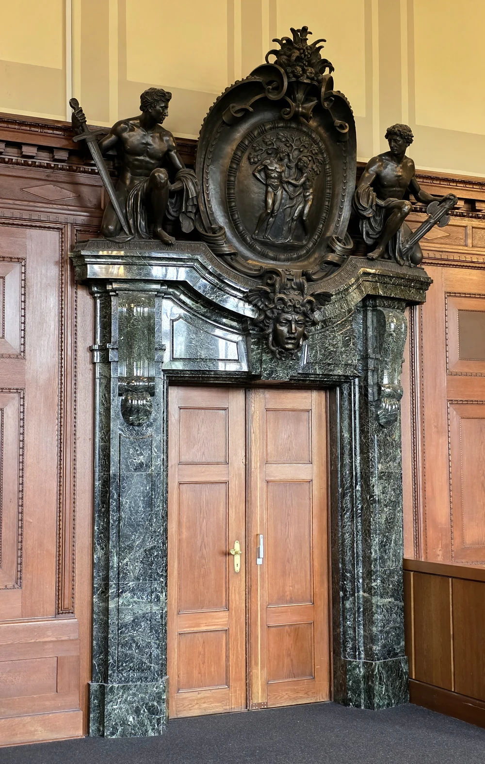 Vista completa do portal da Sala 600, com a Medusa acima da porta, colunas de mármore verde e esculturas em bronze.